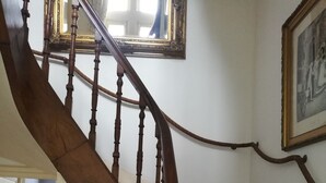 A wooden staircase with a handrail, a framed certificate on the wall, and a radiator in the background. - THE LARGE COTTAGE AT CHÂTEAU SAINTE MARIE NEAR THE MARAIS POITEVIN (Fors)