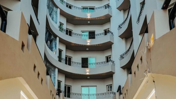 Um átrio com vários níveis, piscina central, varandas em cada andar e design arquitetônico moderno.