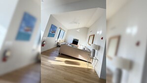 A modern, open-plan living space with a large sofa, a dining area, and a kitchen.