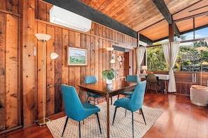 Ein Zimmer mit Holzwandverkleidung, einem Esstisch, Stühlen und einem Blumentopf.