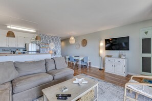 A modern living room with a sofa, coffee table, and a TV mounted on the wall. - Winds V D1 - Oceanfront Pet Friendly Condo with Pool and Close to Boardwalk (Carolina Beach)
