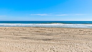 A sandy beach with visible tire tracks and the ocean in the background. - Winds V D1 - Oceanfront Pet Friendly Condo with Pool and Close to Boardwalk (Carolina Beach)
