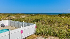 A fenced pool area with a view of the ocean. - Winds V D1 - Oceanfront Pet Friendly Condo with Pool and Close to Boardwalk (Carolina Beach)