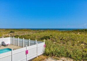 A fenced pool area with a view of the ocean. - Winds V D1 - Oceanfront Pet Friendly Condo with Pool and Close to Boardwalk (Carolina Beach)