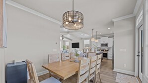 Een moderne keuken met witte kastjes, een magnetron, en een eethoek met een houten tafel en stoelen.