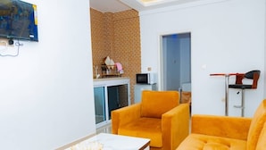 A modern living room with a sofa set, a flat-screen TV, and a decorative bowl on a table. - Elu Hotel Diamant (Douala)