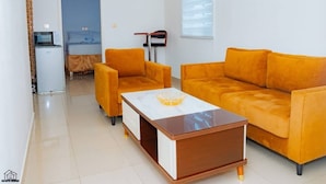 A modern living room with a sofa set, a coffee table, and a microwave. - Elu Hotel Diamant (Douala)