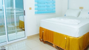 A hotel room with a bed, a sliding glass door, and a window with blinds. - Elu Hotel Diamant (Douala)