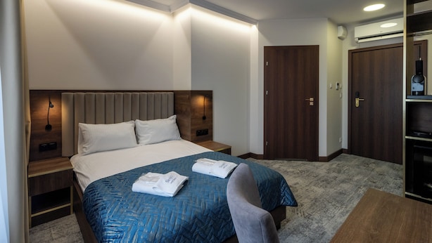 A hotel room with a bed, bedside tables, a wardrobe, and a mirror. - Sleep&Fly Okecie (Warsaw)