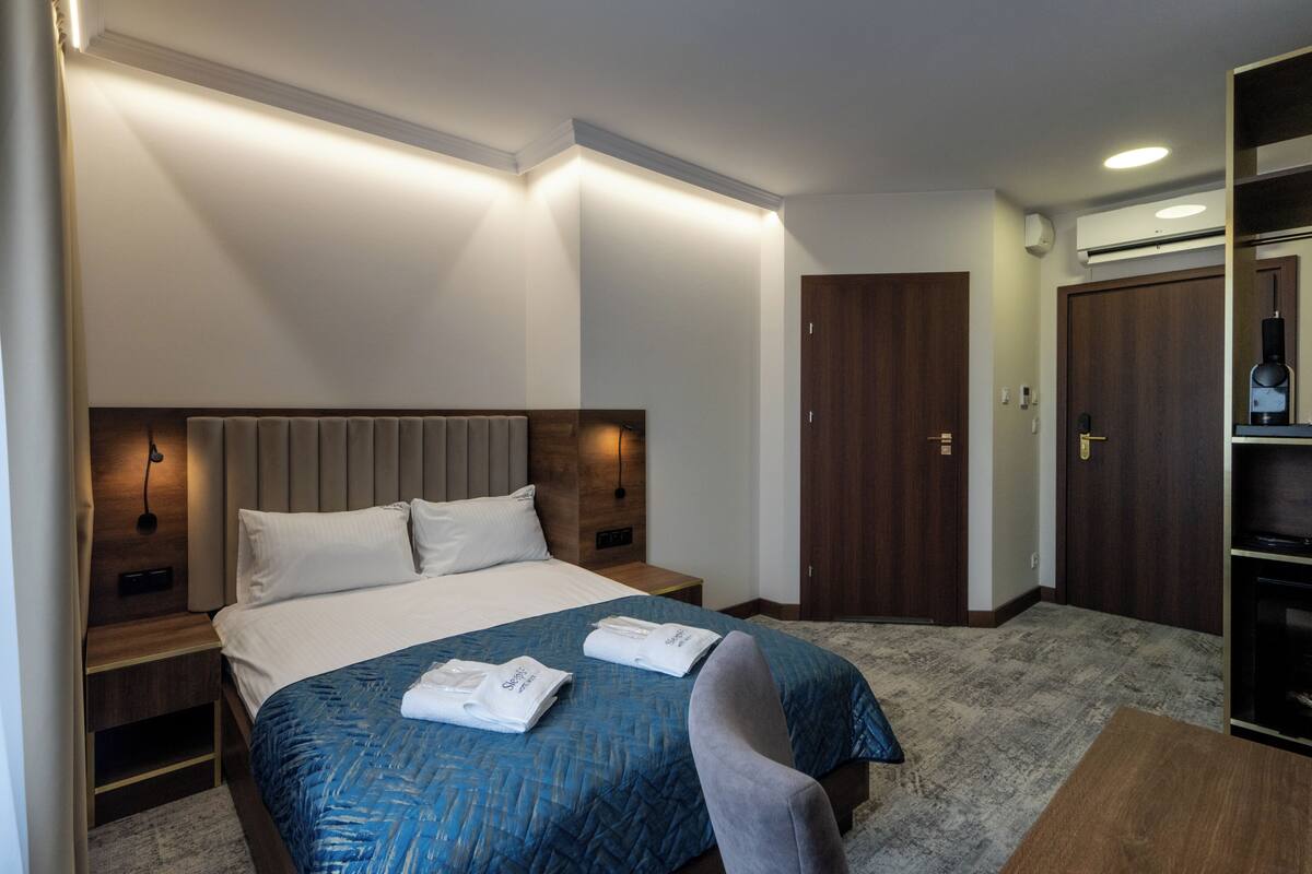 Una habitación de hotel con cama, mesitas de noche, armario y espejo.