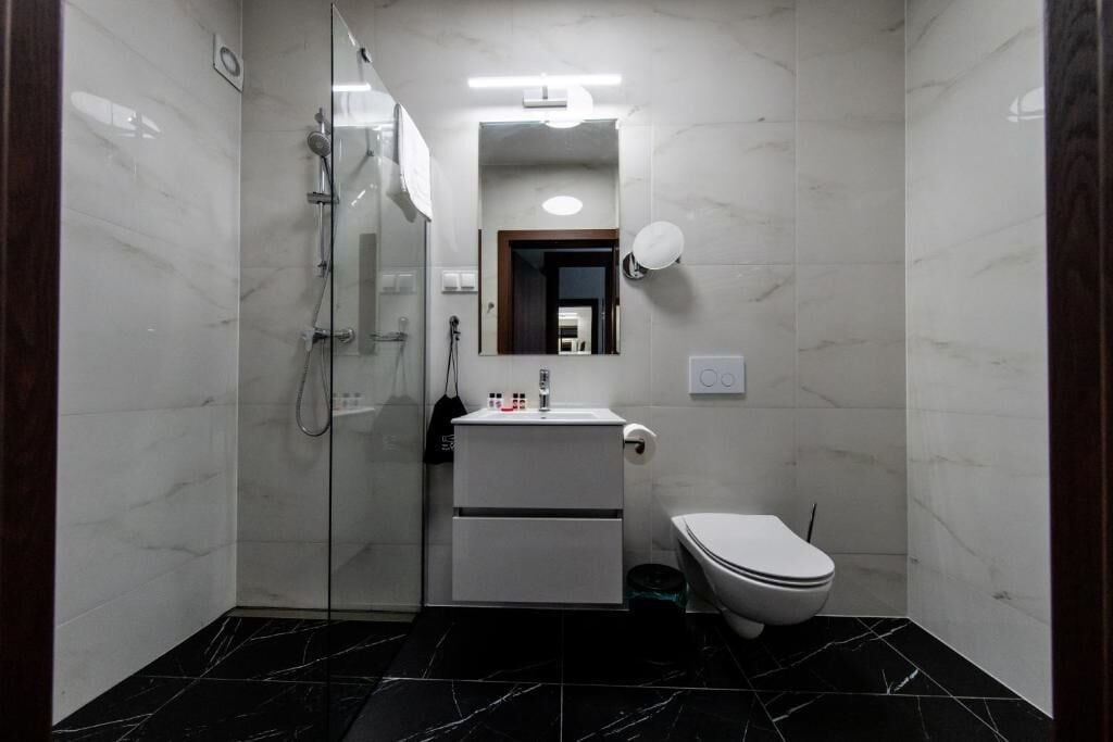 Un baño pequeño con cabina de ducha de vidrio, lavabo blanco y retrete.