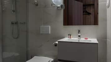 Une salle de bain moderne avec une douche à parois de verre, des toilettes blanches et un meuble-lavabo avec un miroir.