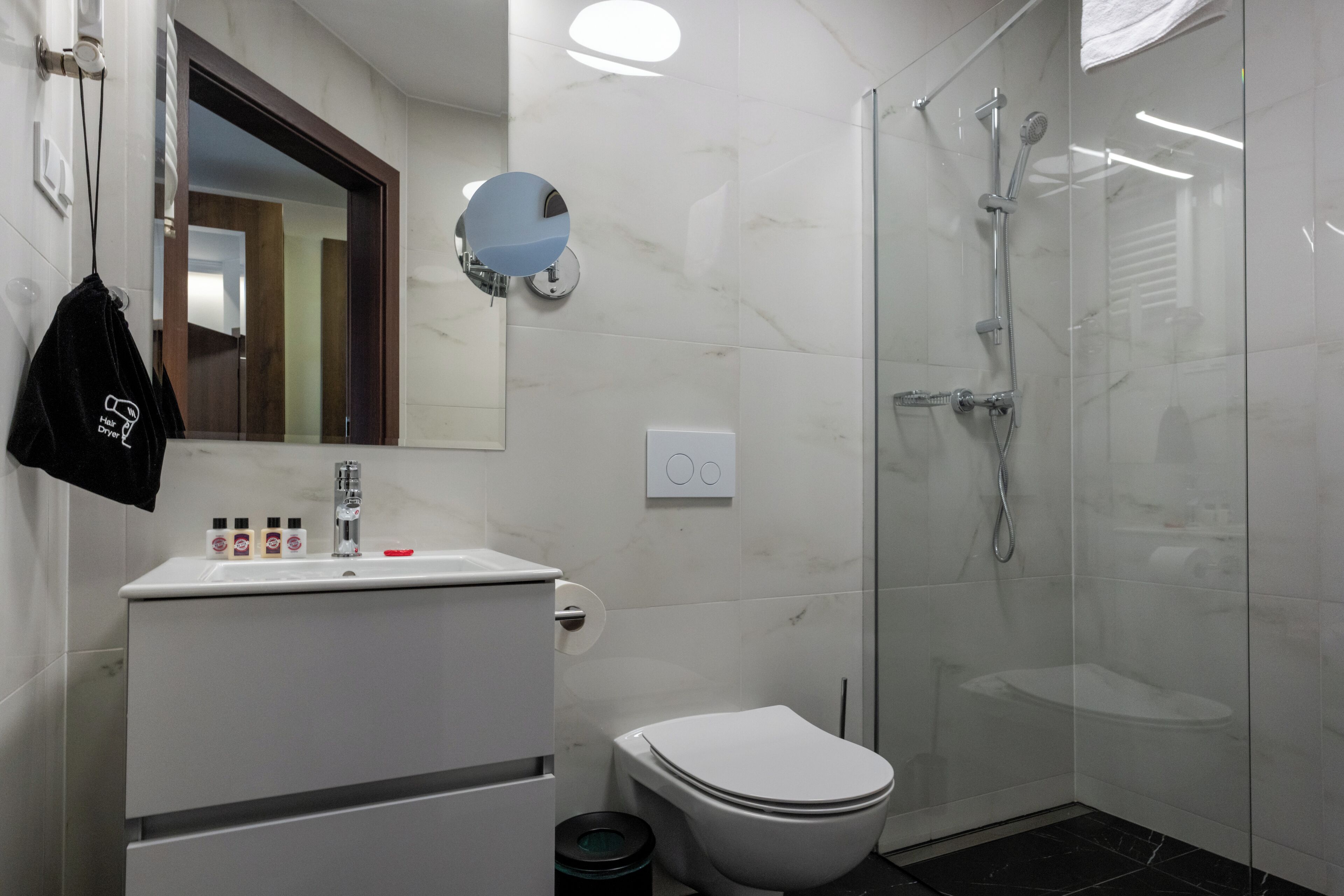 A modern bathroom with a white sink, toilet, and glass shower enclosure.