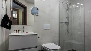 Een moderne badkamer met een wit wastafelmeubel, toilet en een douchecabine van glas.