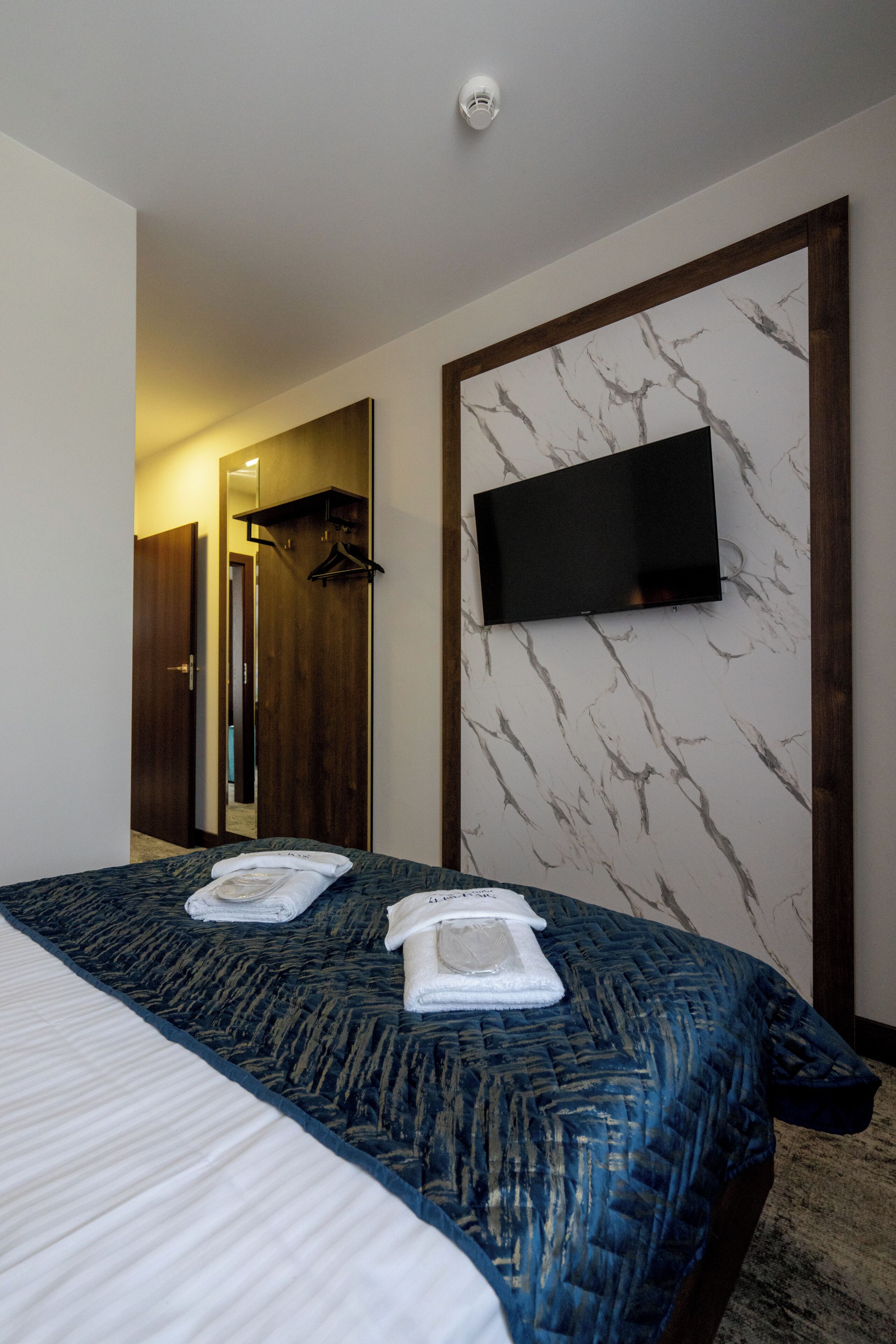 Ein Hotelzimmer mit einem Bett, einem an der Wand montierten Fernseher und einem Holzschrank.