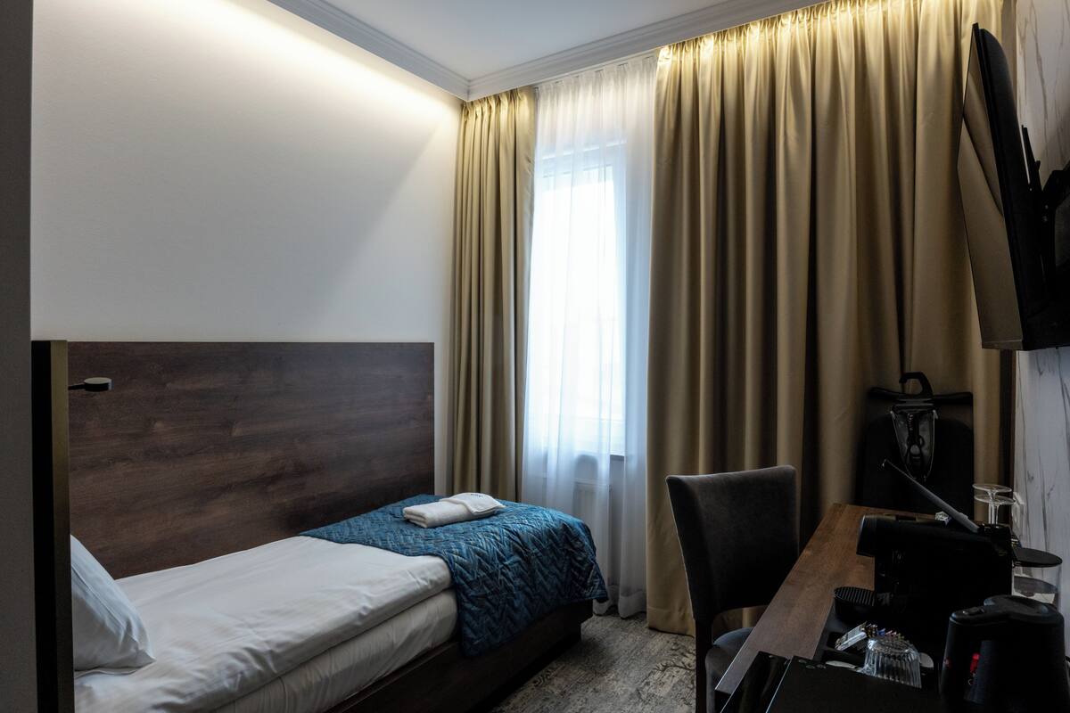 Una habitación de hotel con cama, escritorio, silla, cafetera y televisión.