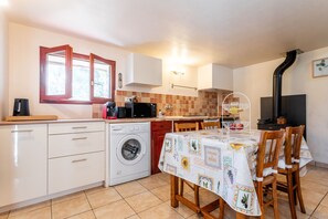 Une cuisine compacte équipée d’un lave-linge, d’un four à micro-ondes et d’un coin repas avec une table pour quatre personnes.