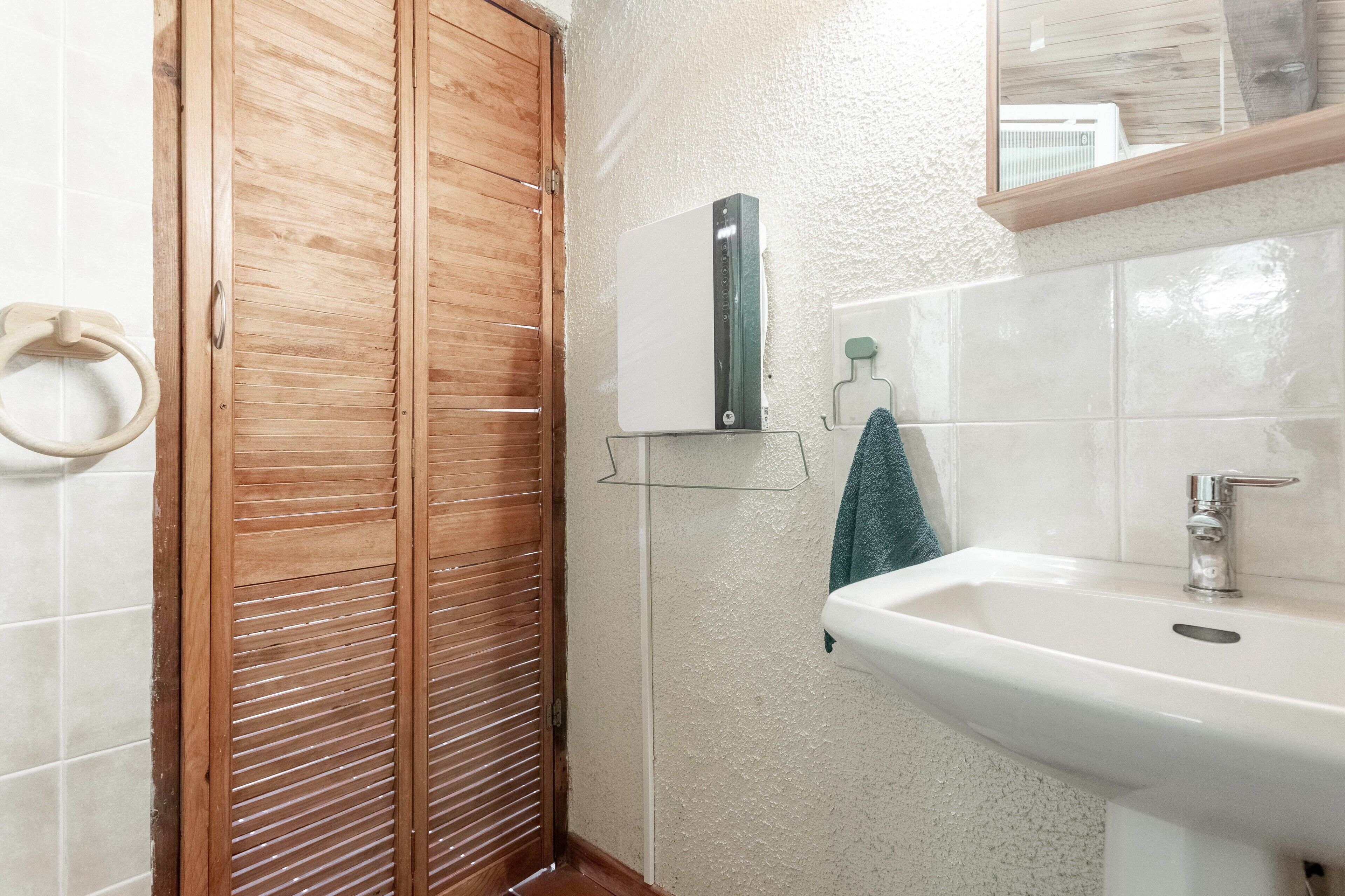 Ein Badezimmer mit Holztür, Waschbecken und Spiegel darüber.