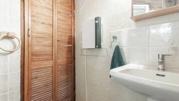 Ein Badezimmer mit Holztür, Waschbecken und Spiegel darüber.