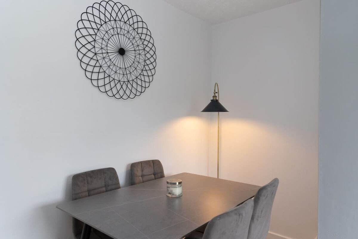 Un coin repas comprenant une table, quatre chaises, un élément décoratif mural et une lampe sur pied.