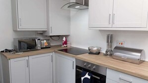 Eine kleine Küche mit weißen Schränken, einer Mikrowelle, einem Toaster und einem Wasserkocher.