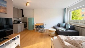 A compact living space with a kitchenette, a dining area, a sofa, and a bed. - Beachfront studio in Scharbeutz - comfort & tranquillity right by the sea (Scharbeutz)