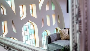 Ein Zimmer mit großem Fenster, einer Couch und einer Wand mit geometrischen Mustern.