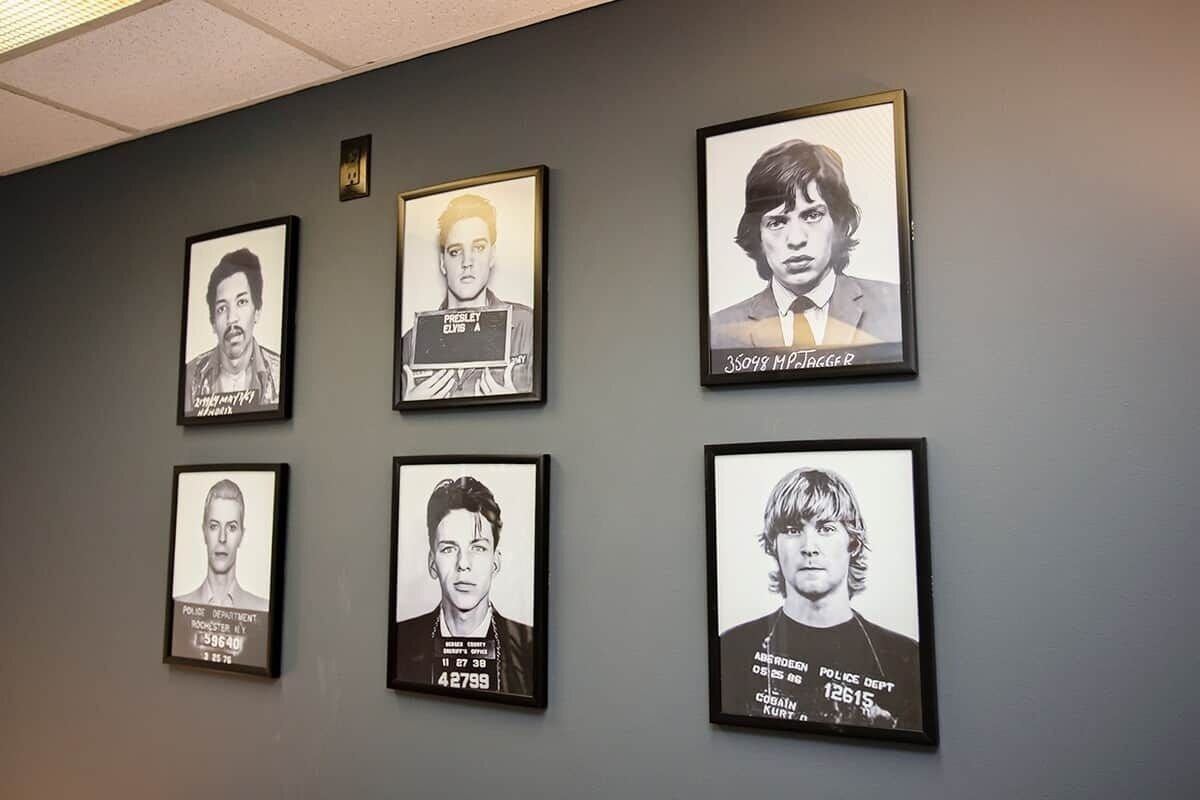 Six framed mugshots on a wall.