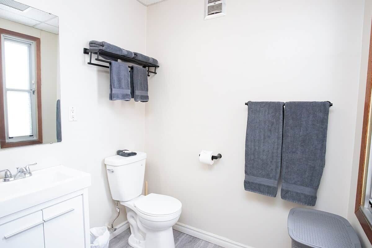 Une salle de bain avec des toilettes blanches, un lavabo et un espace douche.