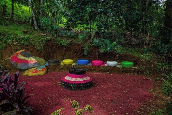 Un jardín con neumáticos de colores dispuestos en círculo, rodeado de follaje.
