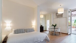 A bedroom with a large bed, bedside lamps, a dining area with a table and chairs, and a view through an open door. - Amazing Duomo loft with terrace and elevator (Florence)