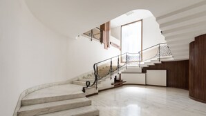 A curved marble staircase with a metal railing leading to a landing. - Amazing Duomo loft with terrace and elevator (Florence)