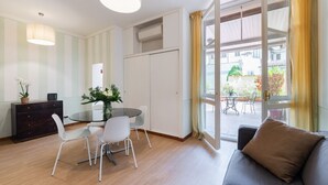 A modern living room with a glass door leading to a balcony, a dining area with a round table and chairs, and a sofa with a cushion. - Amazing Duomo loft with terrace and elevator (Florence)