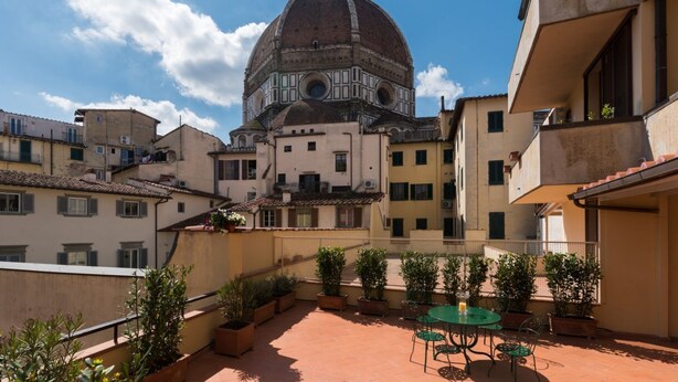 A courtyard with a dome structure, potted plants, and a table with chairs. - Amazing Duomo loft with terrace and elevator (Florence)