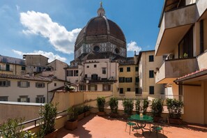 A courtyard with a dome structure, potted plants, and a table with chairs. - Amazing Duomo loft with terrace and elevator (Florence)