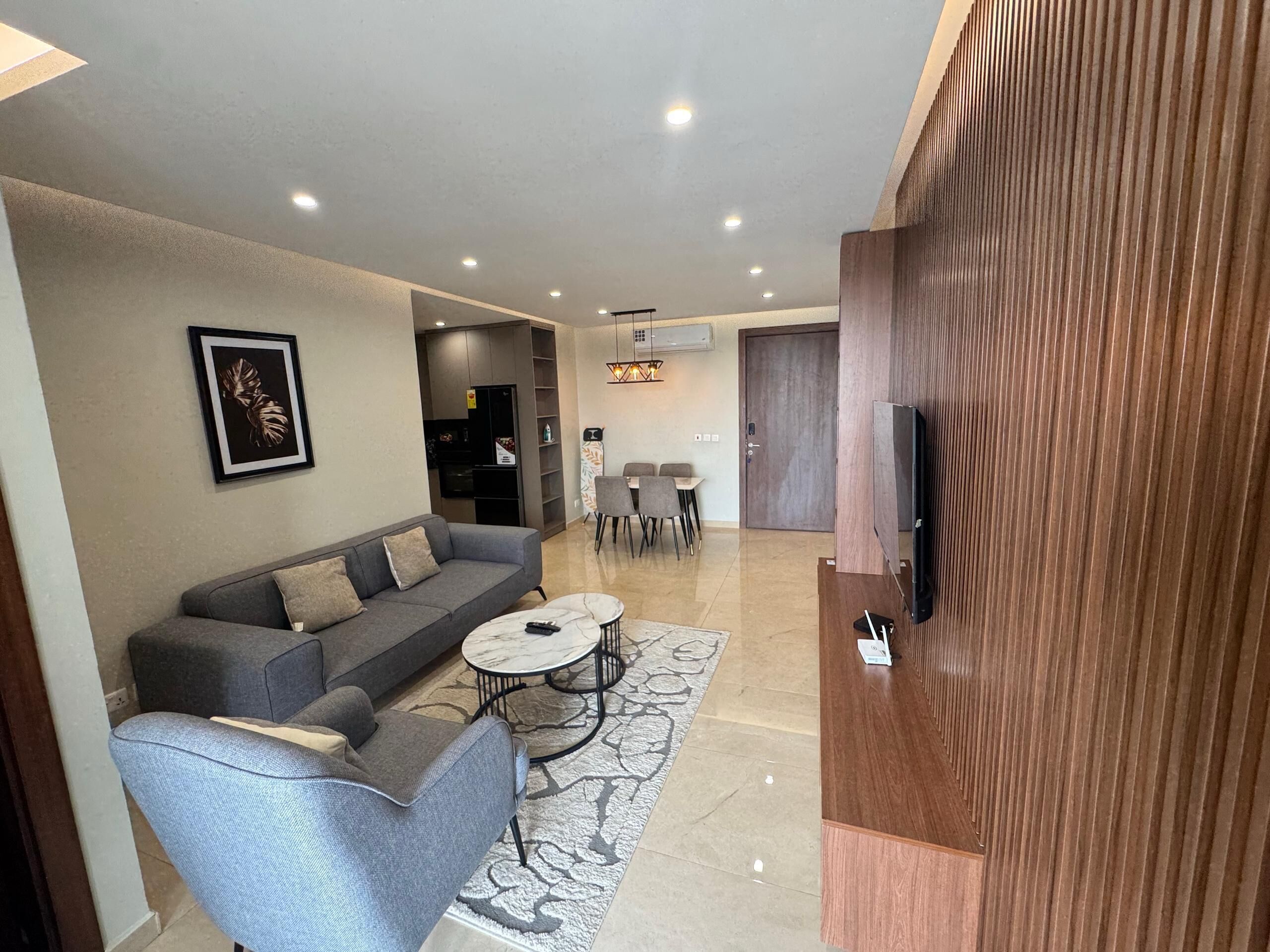 A modern living room with a sofa, armchair, coffee table, and TV stand.