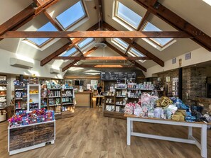 A spacious store with high ceilings and skylights, wooden beams, and various items on shelves and tables.