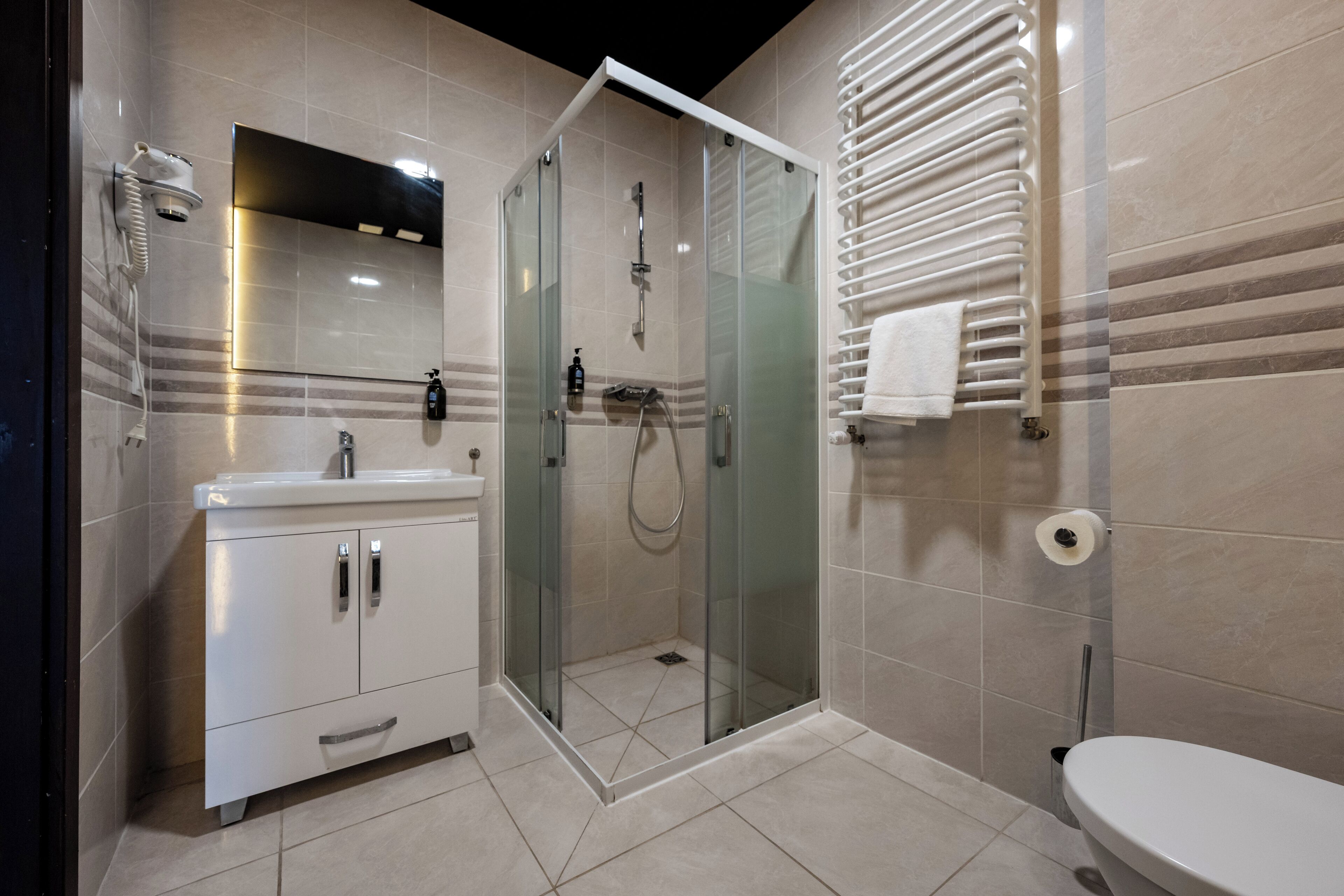 A modern bathroom with a glass-enclosed shower, a white sink, and a toilet.