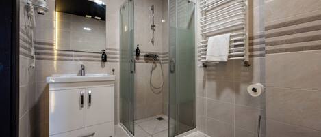 A modern bathroom with a glass-enclosed shower, a white sink, and a toilet.