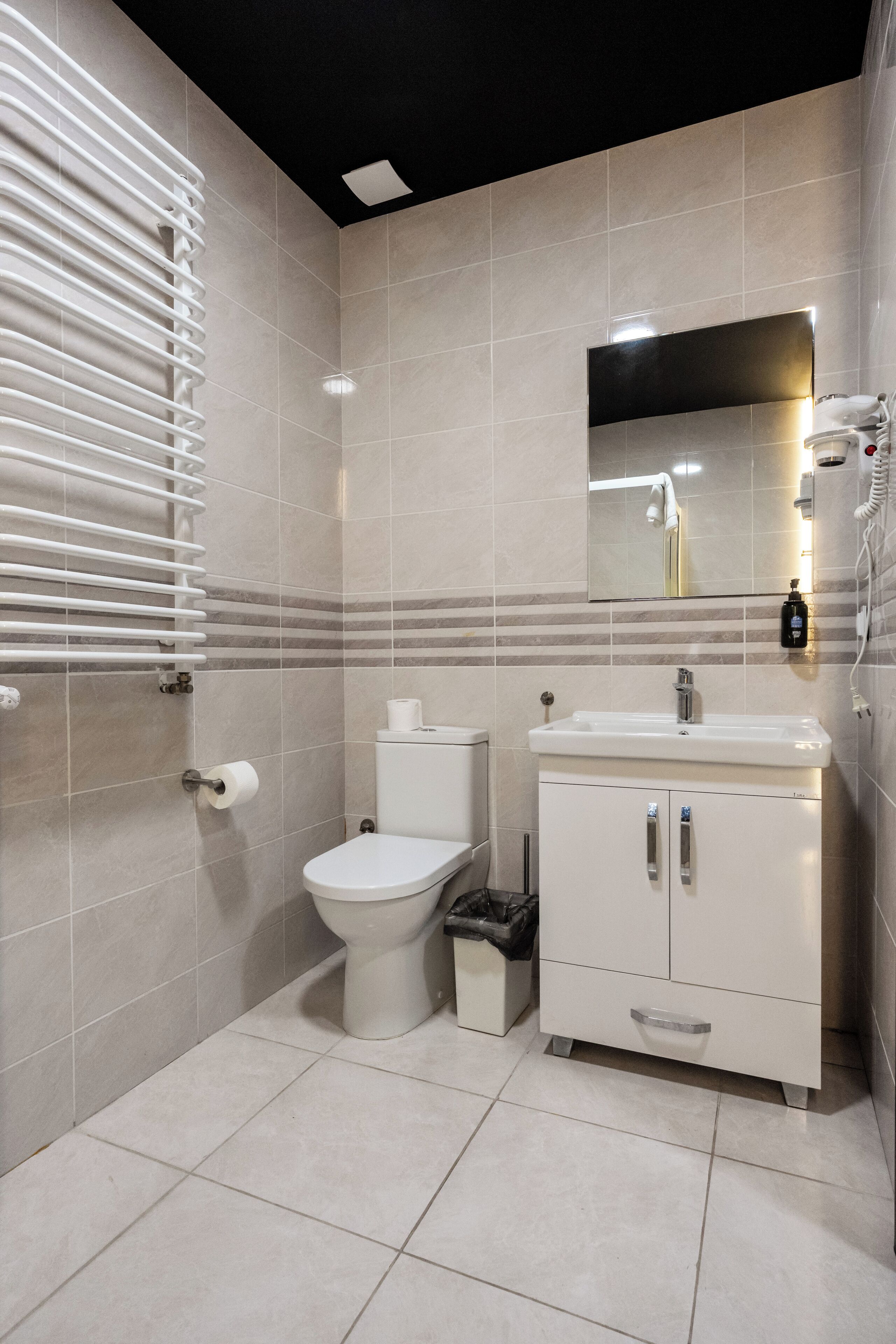 A modern bathroom with a toilet, sink, and mirror.