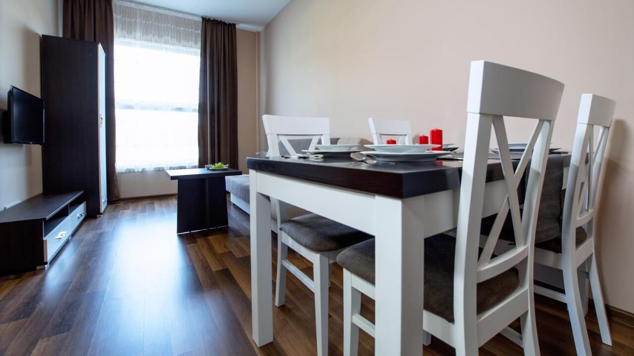 Un comedor moderno con una mesa, sillas y un televisor sobre un mueble.