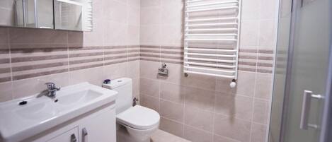 Een badkamer met een wastafel, toilet en een douchecabine van glas.