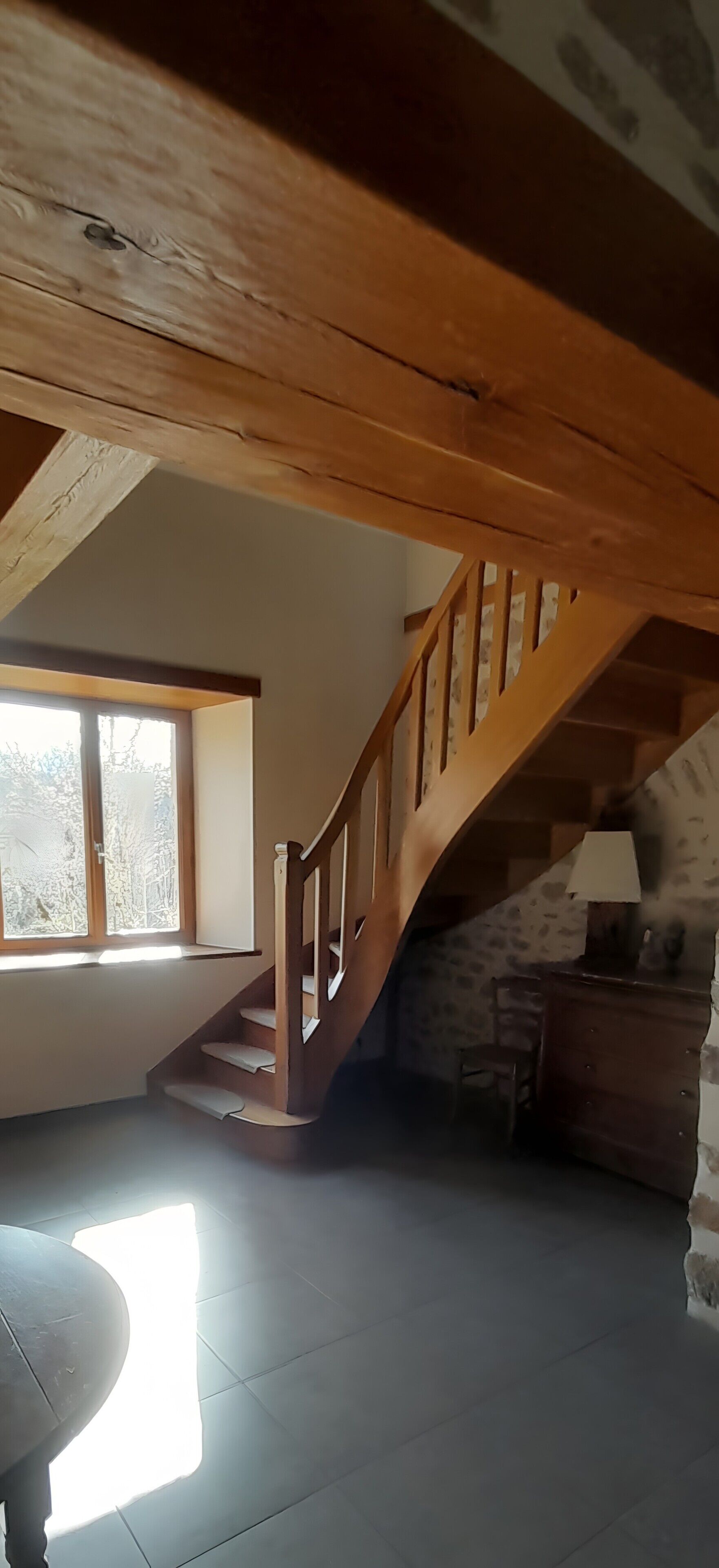 Una scala in legno con un muro in pietra e una lampada.