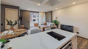Un salon moderne comprenant un coin repas, un canapé, un téléviseur et une grande fenêtre.