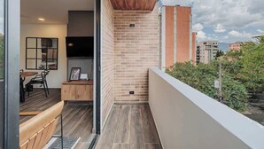 Un balcon moderne avec un plafond en bois, des murs en briques et une vue sur les bâtiments environnants.
