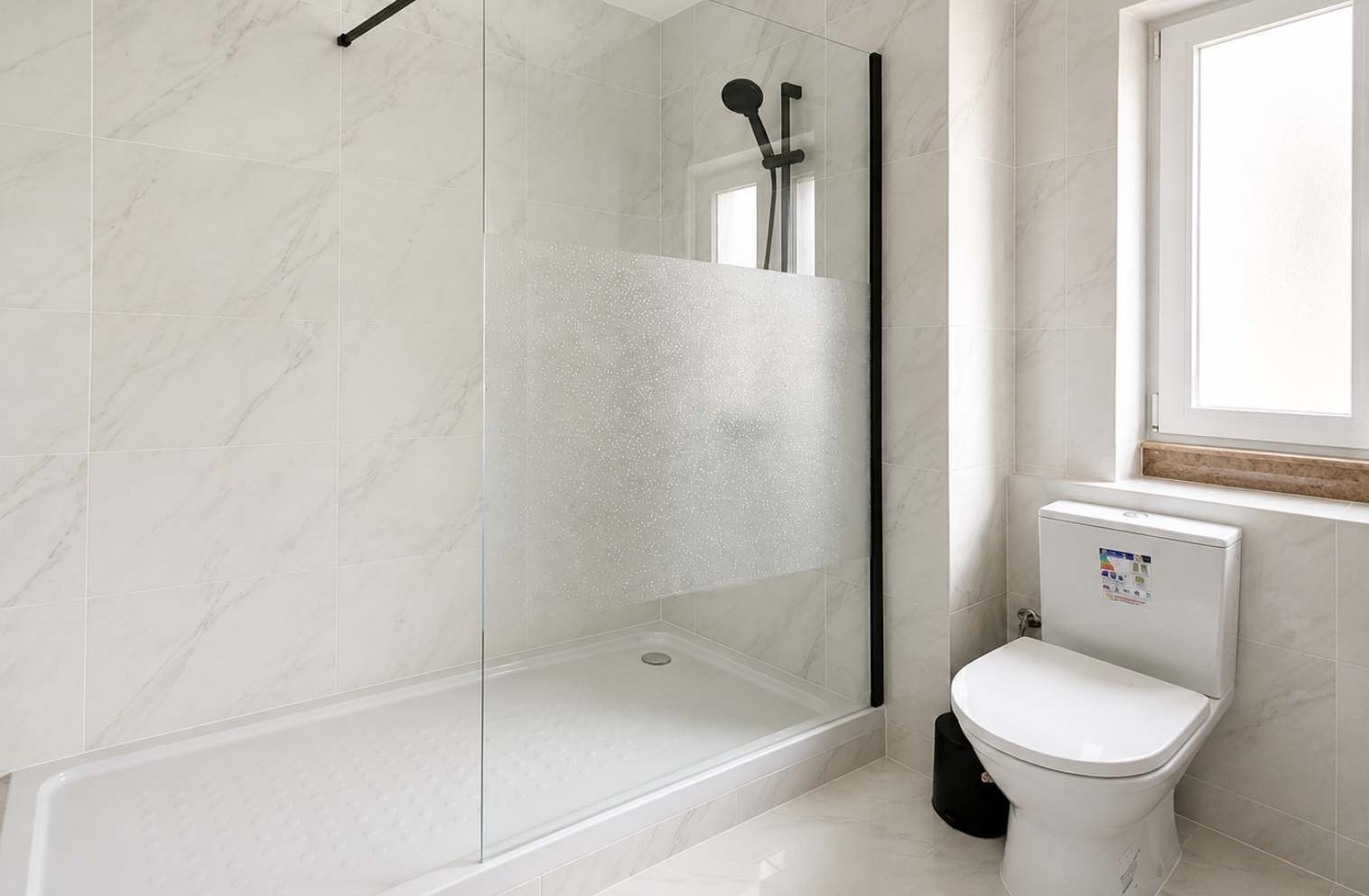 Un baño con ducha acristalada, inodoro blanco y ventana.