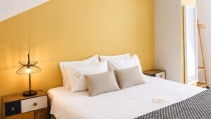 Un dormitorio con cama, mesitas de noche, una lámpara y un equipo de aire acondicionado.