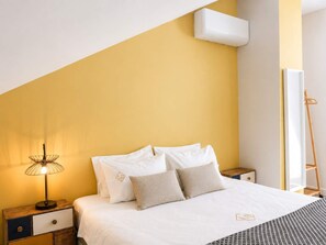 Ein Schlafzimmer mit einem Bett, Nachttischen, einer Lampe und einer Klimaanlage.