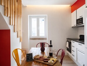 A kitchen with a dining table set for a meal, featuring a wine bottle, glasses, and a variety of cheeses and meats. - Spacious Gulbenkian – Families, A/C & Remote Work (Lisboa)