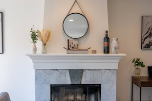 A fireplace mantel with a mirror, a book, a bottle, and decorative items. - King Bed Studio w/ Full Kitchen in Lower Haight (San Francisco)